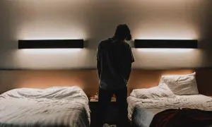 Młody mężczyzna stoi w pokoju hotelowym z dwoma łóżkami. Czy osoba niepełnoletnia może zameldować się w hotelu?