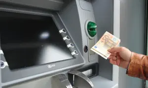 Ręka trzyma banknoty euro przy bankomacie. Tak, w Grecji jest euro.