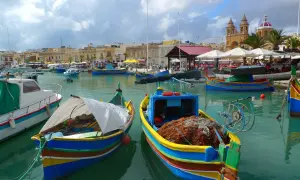 Kolorowe łodzie rybackie w porcie Marsaxlokk. Czy na Malcie jest drogo? Widok sugeruje, że życie toczy się tu spokojnie, a ceny mogą być przystępne.