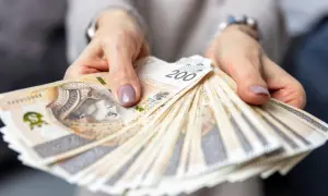 Dłonie trzymają wachlarz banknotów 200 zł. Zastanawiasz się, ile zarabia hotelarz?