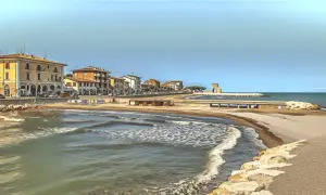 Spokojne morze i plaża w Rimini, z budynkami w tle. Czy Rimini jest bezpieczne? Wygląda na spokojne i przyjazne.