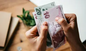 Ręce trzymają banknoty 10 i 20 lir tureckich. Planujesz podróż i zastanawiasz się, jaką walutę zabrać do Turcji? Lira turecka to odpowiedź!