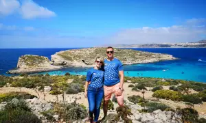 Para na tle turkusowej wody i skalistego krajobrazu Malty. Ile ludności ma Malta? Około 500 tysięcy.