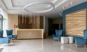 Nowoczesne lobby hotelowe z wygodnymi fotelami, recepcją i designerskim oświetleniem.