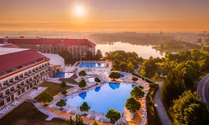 Hotel Gołębiewski w Mikołajkach, z basenami i jeziorem w tle, o wschodzie słońca. Ile lat ma hotel Gołębiewski w Mikołajkach?