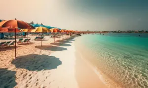 Piękna plaża z rzędem parasoli i leżaków, turkusowa woda i ludzie kąpiący się w morzu. Czy Djerba jest bezpieczna? Wygląda na spokojną i relaksującą.