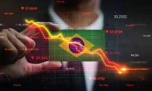 Ręka trzyma flagę Brazylii na tle wykresu finansowego. Kiedyś waluta Brazylii, real, doświadcza spadków.