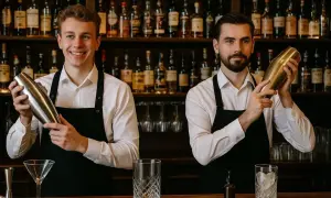 Dwóch barmanów w fartuchach przygotowuje drinki. Zastanawiasz się, ile zarabia barman?