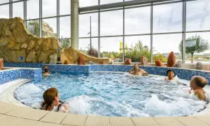 Ludzie relaksują się w jacuzzi. Szukając, które termy są najtańsze, warto sprawdzić oferty z podobnymi atrakcjami.