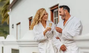 Para, która cieszy się szampanem na balkonie w hotelowych szatach. Zastanawiasz się, ile kosztuje doba hotelowa w takim miejscu?