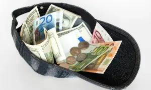 Czapka wypełniona banknotami dolarów i euro, a także monetami. Czy w Turcji można płacić dolarami? Ta wizualizacja sugeruje, że tak, bo pieniądze są wszędzie!