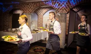 Kelnerzy niosą talerze z jedzeniem. Zastanawiasz się, jak się ubrać na kolację all inclusive? Elegancko, ale wygodnie, jak obsługa.