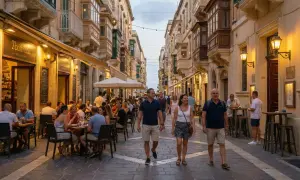 Ludzie spacerują i jedzą w restauracjach na maltańskiej uliczce. Czy Malta jest zagrożona? Wygląda na to, że tętni życiem.
