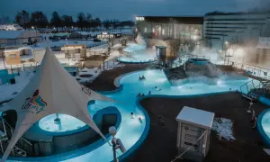 Gdzie są Termy Uniejów? W zimowy wieczór ludzie relaksują się w podgrzewanych basenach zewnętrznych kompleksu.