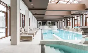 Luksusowy basen hotelowy z leżakami i jacuzzi. Zastanawiasz się, ile kosztuje jedna noc w hotelu z takim zapleczem?