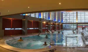 Ludzie relaksują się w basenie termalnym z hydromasażem. Czy na termach trzeba mieć czepek? Tutaj nie widać żadnych czepków.