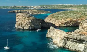 Malta w lutym: rejs łodzią po turkusowych wodach, skaliste wybrzeża i widok na miasto w oddali. Idealne miejsce na odkrywanie!