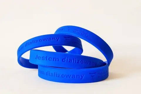Niebieska opaska na ręce z napisem "Jestem dializowany" i logo Fresenius Medical Care.
