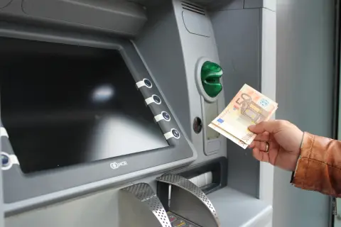 Ręka trzyma banknoty euro przy bankomacie. Tak, w Grecji jest euro.
