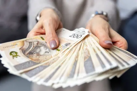 Dłonie trzymające plik banknotów 200 zł. Czy to odpowiedź na pytanie, ile zarabia menedżer hotelu?
