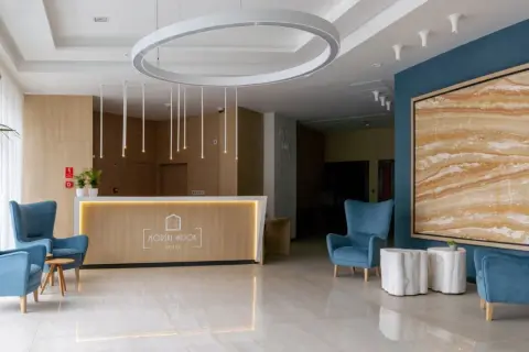 Nowoczesne lobby hotelowe z wygodnymi fotelami, recepcją i designerskim oświetleniem.