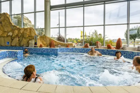 Ludzie relaksują się w jacuzzi. Szukając, które termy są najtańsze, warto sprawdzić oferty z podobnymi atrakcjami.