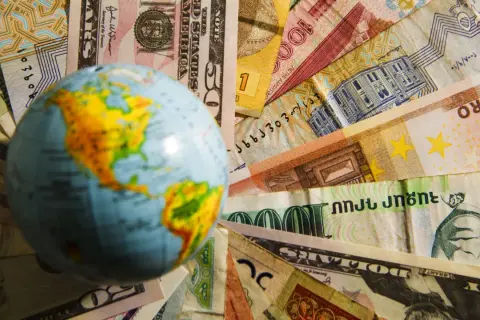 Globus na tle różnych walut. Czy na Malcie można płacić dolarami? To pytanie zadaje sobie wielu podróżnych.