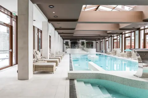Luksusowy basen hotelowy z leżakami i jacuzzi. Zastanawiasz się, ile kosztuje jedna noc w hotelu z takim zapleczem?
