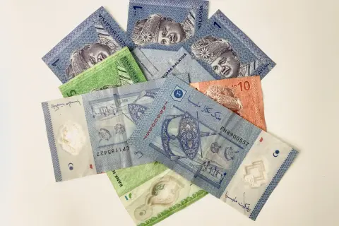 Malezyjskie banknoty, w tym 1 RM i 10 RM, z wizerunkiem króla.