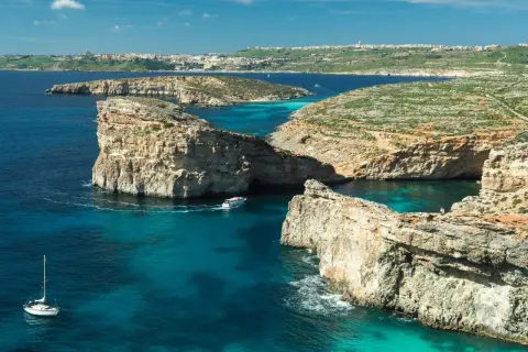 Malta w lutym: rejs łodzią po turkusowych wodach, skaliste wybrzeża i widok na miasto w oddali. Idealne miejsce na odkrywanie!