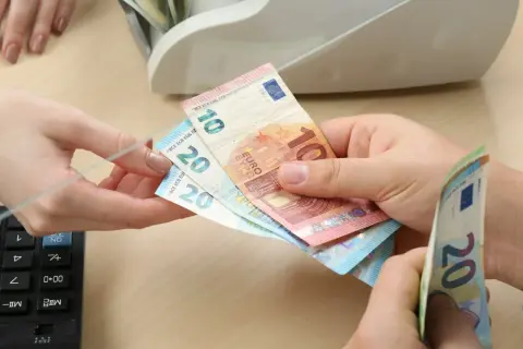 Ręce przekazują sobie banknoty euro. Czy na Węgrzech można płacić euro? Tak, w wielu miejscach można.