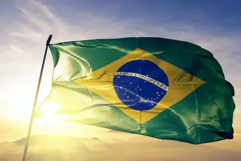 Flaga Brazylii powiewa na tle nieba. Czy jest waluta o nazwie real? Tak, to brazylijska waluta.