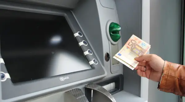 Ręka trzyma banknoty euro przy bankomacie. Tak, w Grecji jest euro.