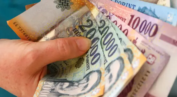 Dłoń trzyma stos węgierskich forintów. Zastanawiasz się, gdzie wymienić forinty? Warto sprawdzić kursy w kantorach lub bankach.