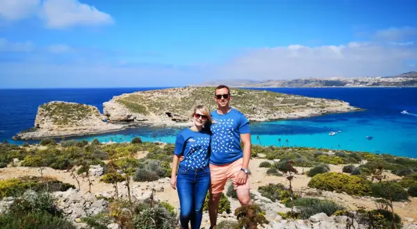 Para na tle turkusowej wody i skalistego krajobrazu Malty. Ile ludności ma Malta? Około 500 tysięcy.