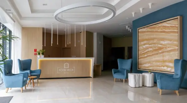 Nowoczesne lobby hotelowe z wygodnymi fotelami, recepcją i designerskim oświetleniem.