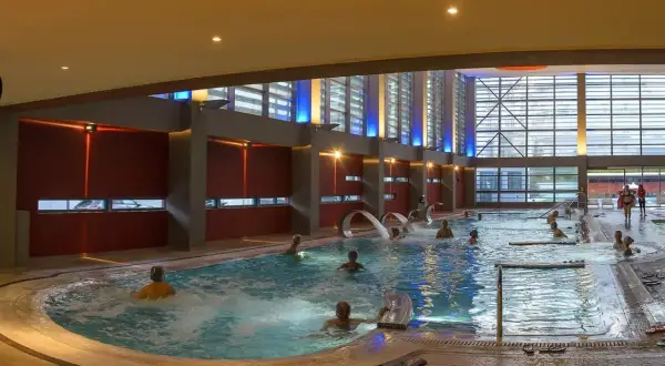 Ludzie relaksują się w basenie termalnym z hydromasażem. Czy na termach trzeba mieć czepek? Tutaj nie widać żadnych czepków.