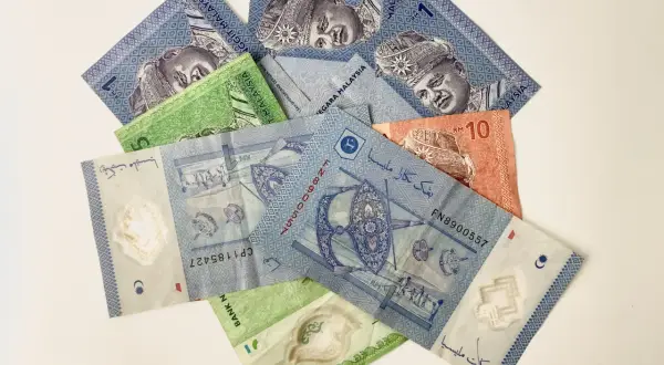 Malezyjskie banknoty, w tym 1 RM i 10 RM, z wizerunkiem króla.