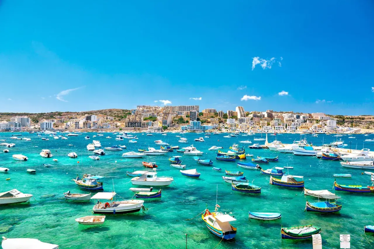 Malta w lutym: słoneczna zatoka pełna łodzi, idealna na spacer.