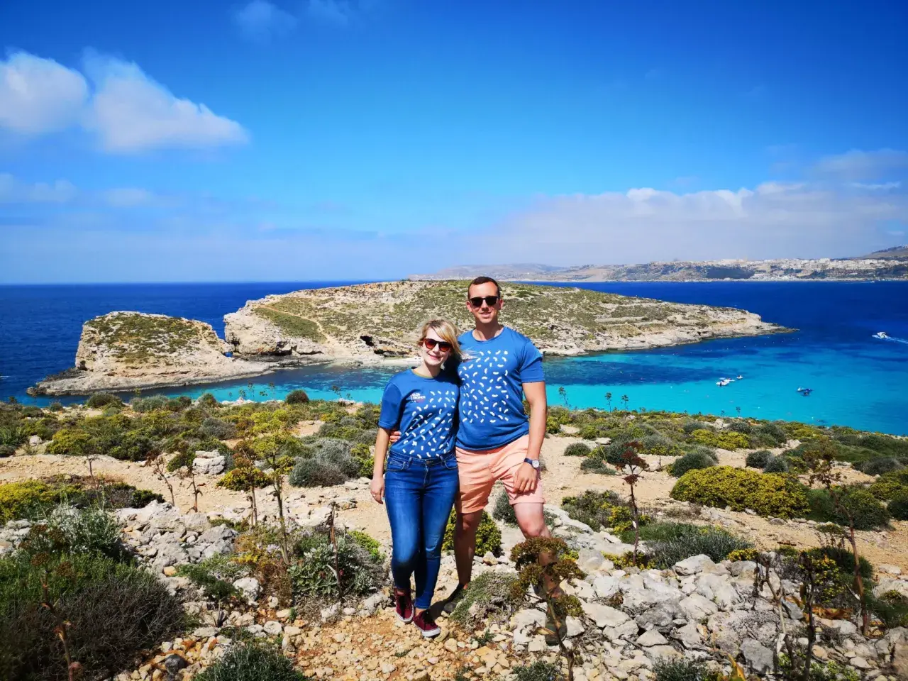Para na tle turkusowej wody i skalistego krajobrazu Malty. Ile ludności ma Malta? Około 500 tysięcy.