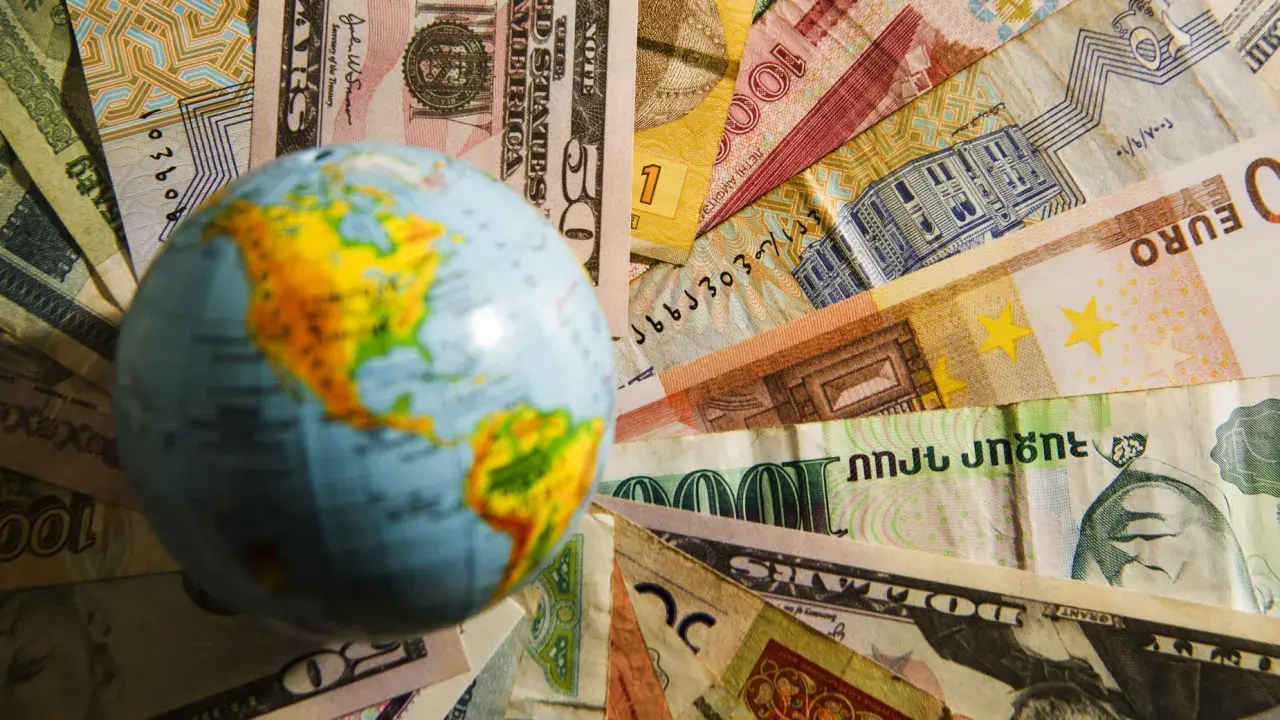Globus na tle różnych walut. Czy na Malcie można płacić dolarami? To pytanie zadaje sobie wielu podróżnych.