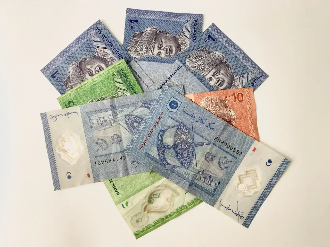 Malezyjskie banknoty, w tym 1 RM i 10 RM, z wizerunkiem króla.