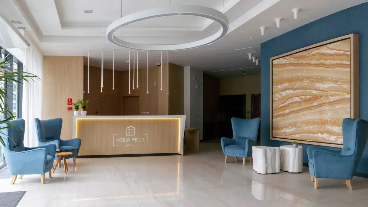 Nowoczesne lobby hotelowe z wygodnymi fotelami, recepcją i designerskim oświetleniem.