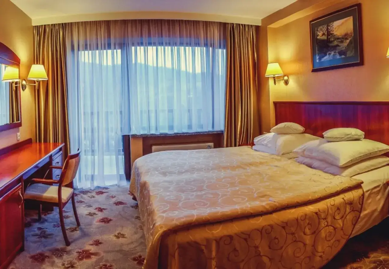 Przytulny pokój hotelowy z dużym łóżkiem, biurkiem i widokiem na góry. Ile pokoi ma Hotel Gołębiewski w Wiśle?
