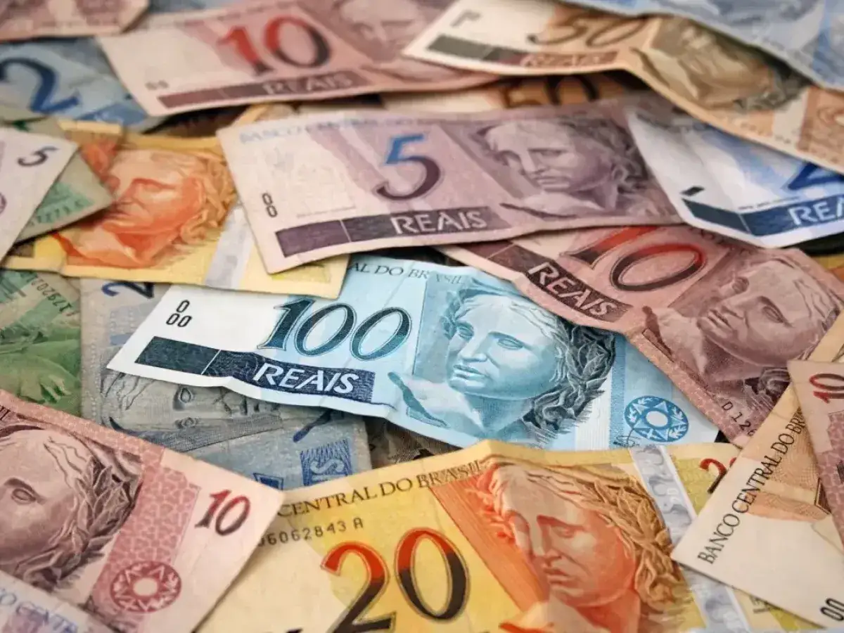 Stos banknotów, w tym 100, 50, 20, 10 i 5 reali. Czy jest waluta o nazwie real? Tak, to brazylijski real.
