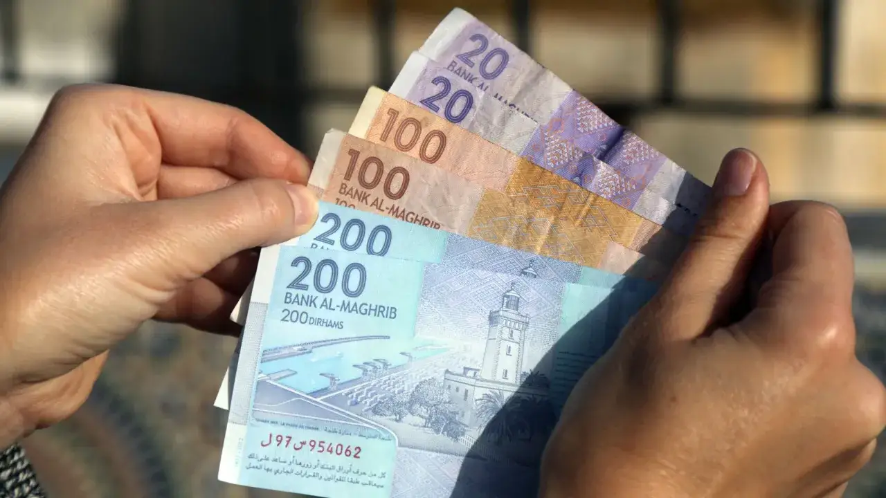 Ręka trzyma marokańskie dirhamy. Czy w Maroko można płacić dolarami? Lepiej mieć lokalną walutę.