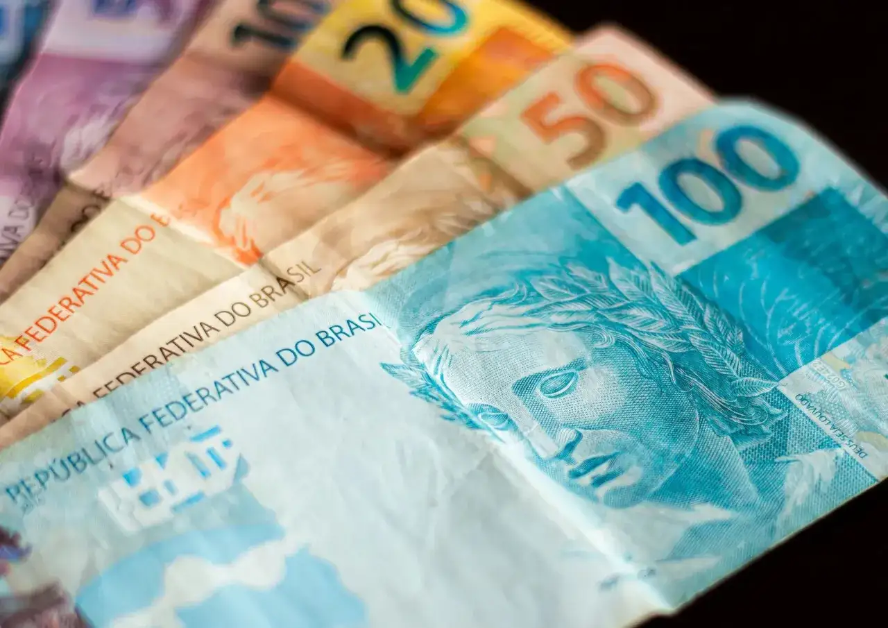 Różne nominały brazylijskiej waluty, real, ułożone wachlarzowo. Widoczne banknoty 100, 50, 20 i inne.