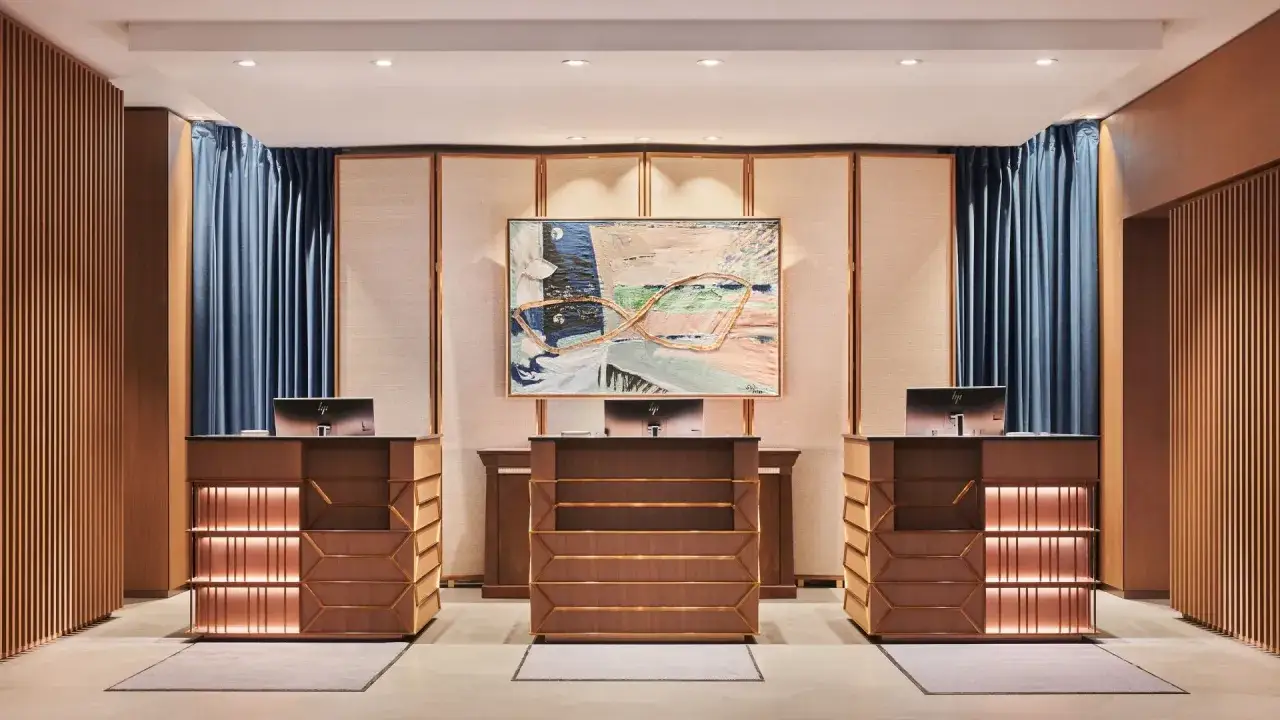 Eleganckie lobby hotelowe z recepcją, nowoczesnym obrazem i drewnianymi panelami.