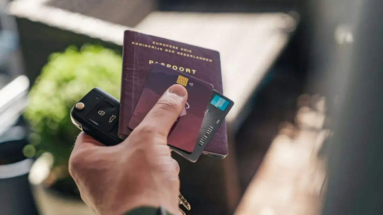 Dłoń trzyma kluczyki, paszport i karty płatnicze. Włochy, podobnie jak inne kraje strefy euro, używają euro.