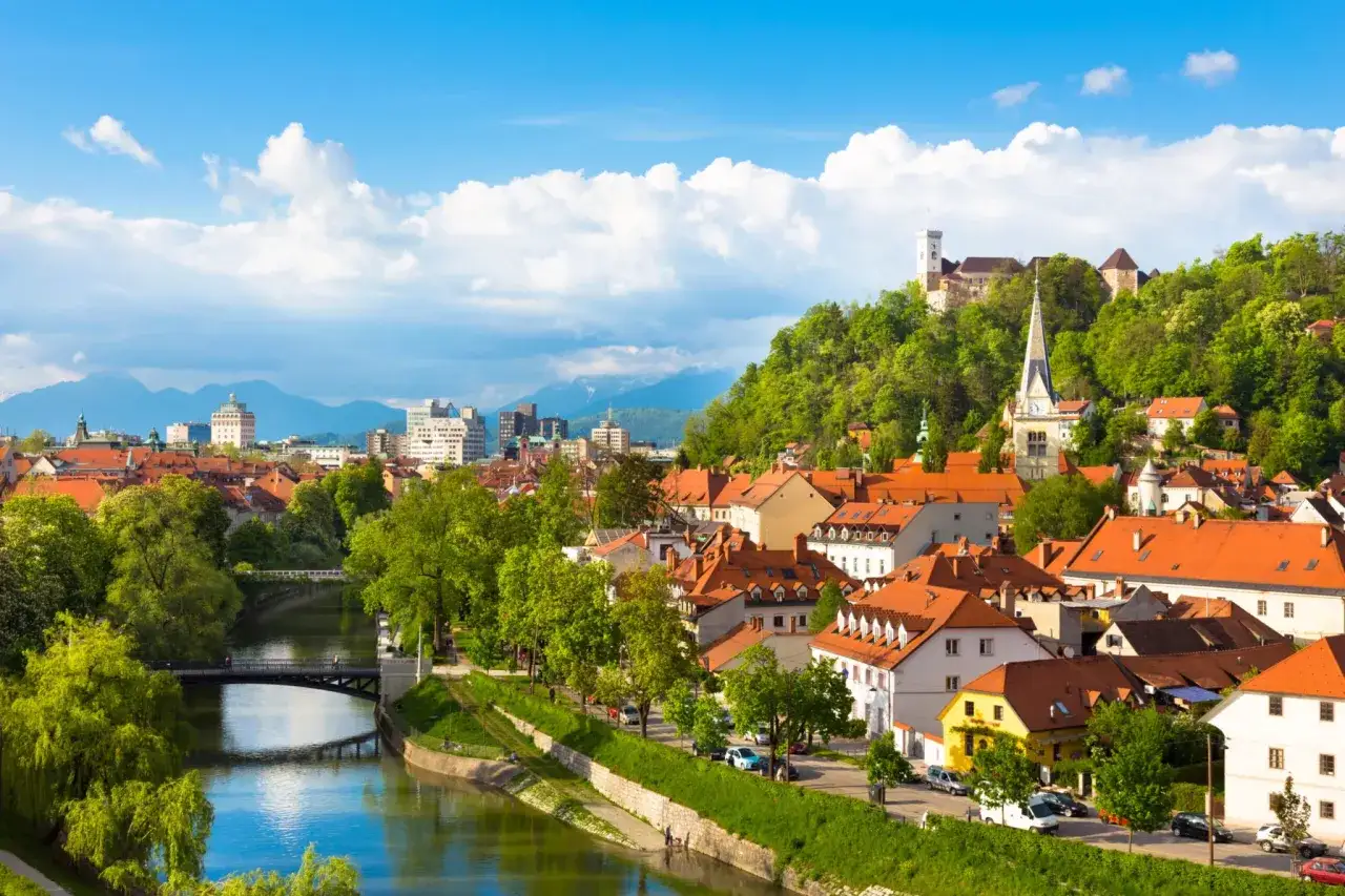 Lublana, Słowenia. W tle zamek na wzgórzu, a na pierwszym planie rzeka i urokliwe kamienice. Tu obowiązuje euro, czyli jaką walutę ma Słowenia.